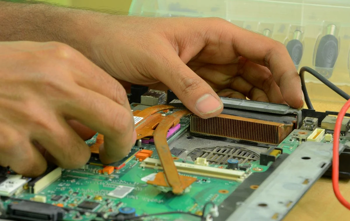 Technician repairing an open desktop computer at a workbench